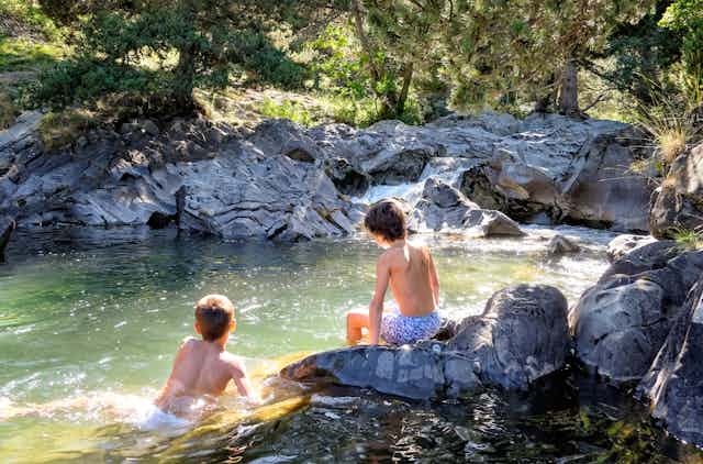 Deux jeunes garçons se baignent dans une eau verdâtre