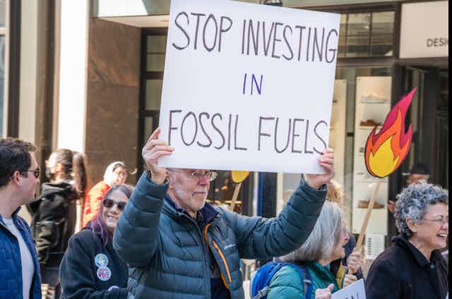 Manifestante con una pancarta que dice: "Stop investing in fossil fuels".
