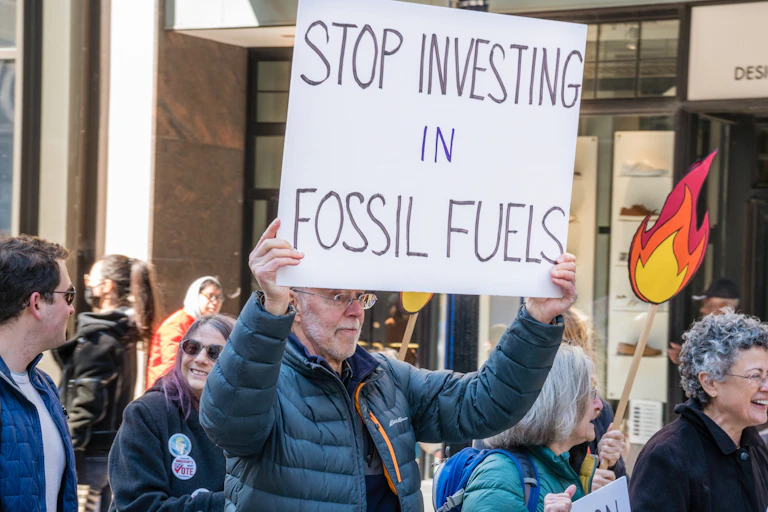 Manifestante con una pancarta que dice: "Stop investing in fossil fuels".