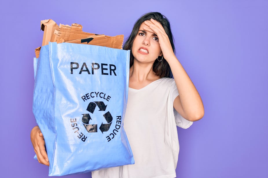 Woman holding recycling bag looking confused.
