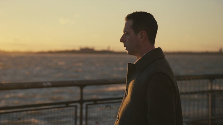 Jeremy Strong stares into the ocean while the sun sets.