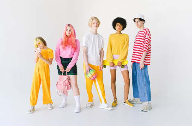 Cinq jeunes personnes portant des vêtements multicolores.