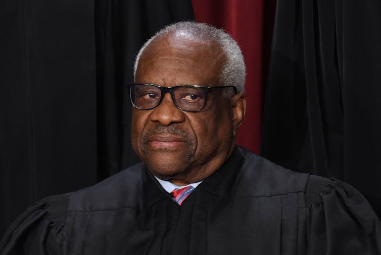 An older man with glasses and gray hair in a black judicial robe.