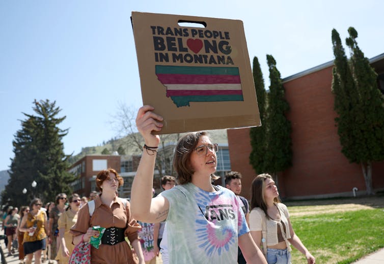 Young activists marching with a woman ahead holding a sign that says 'trans people belong in Montana.'