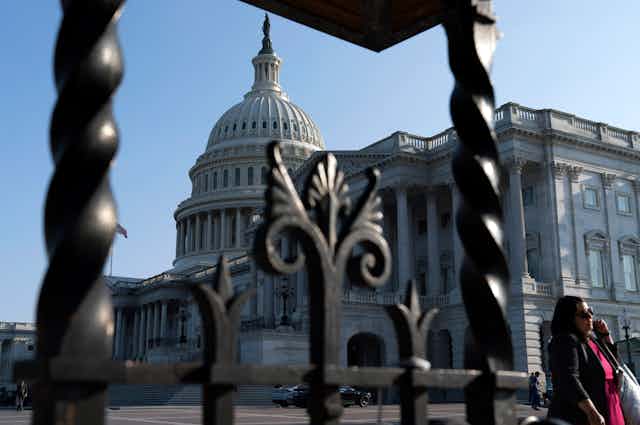 The US capitol dome seen behind an iron fence.