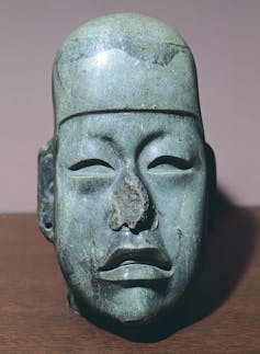A jade figurine of a head, with eyes that appear to be closing.