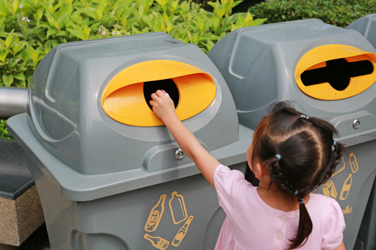 Girl putting rubbish in recycling bin