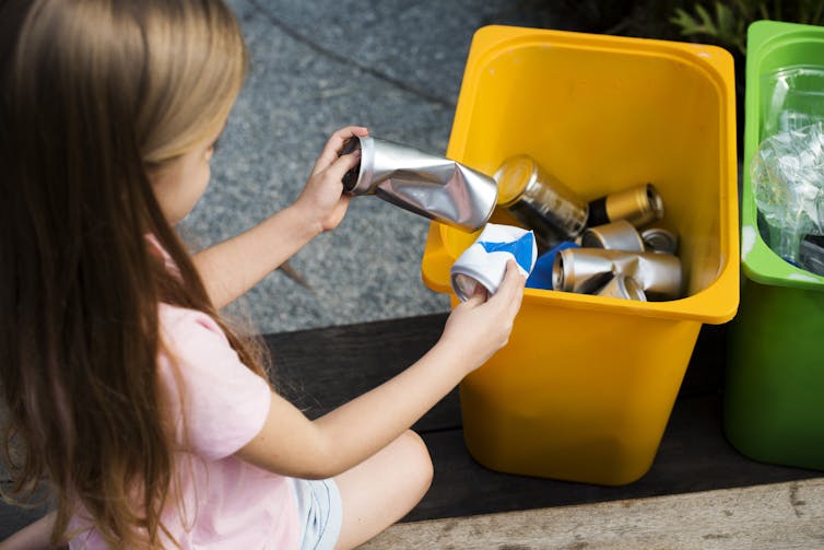 Girl sorting cans into recycling bin