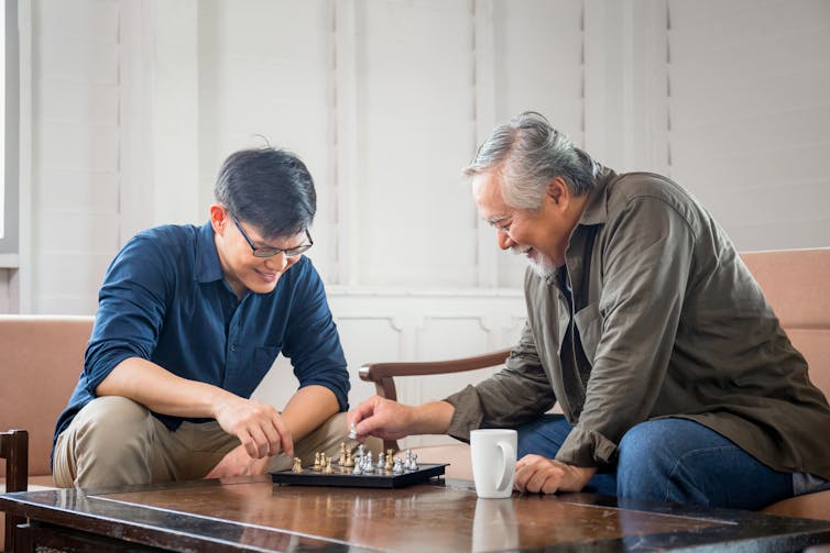 A young man playing chess with an older man.