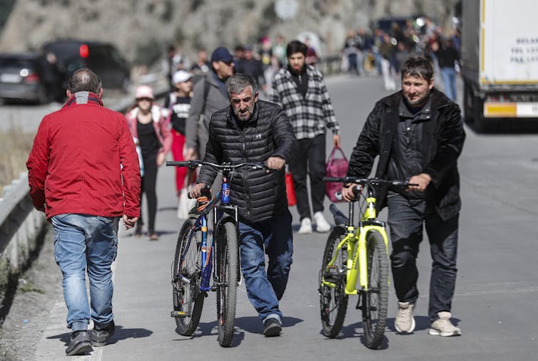 Russian men, some pushing bicycles, make their way to Russia's border with Georgia, September 2022.