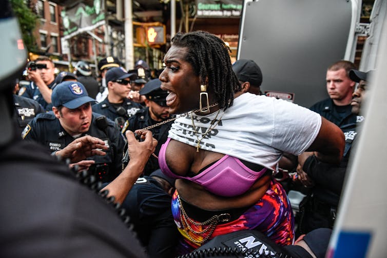 A person cries out while being handled by police officers.