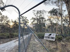 A tall fence with a sign that says 'electric fence'.