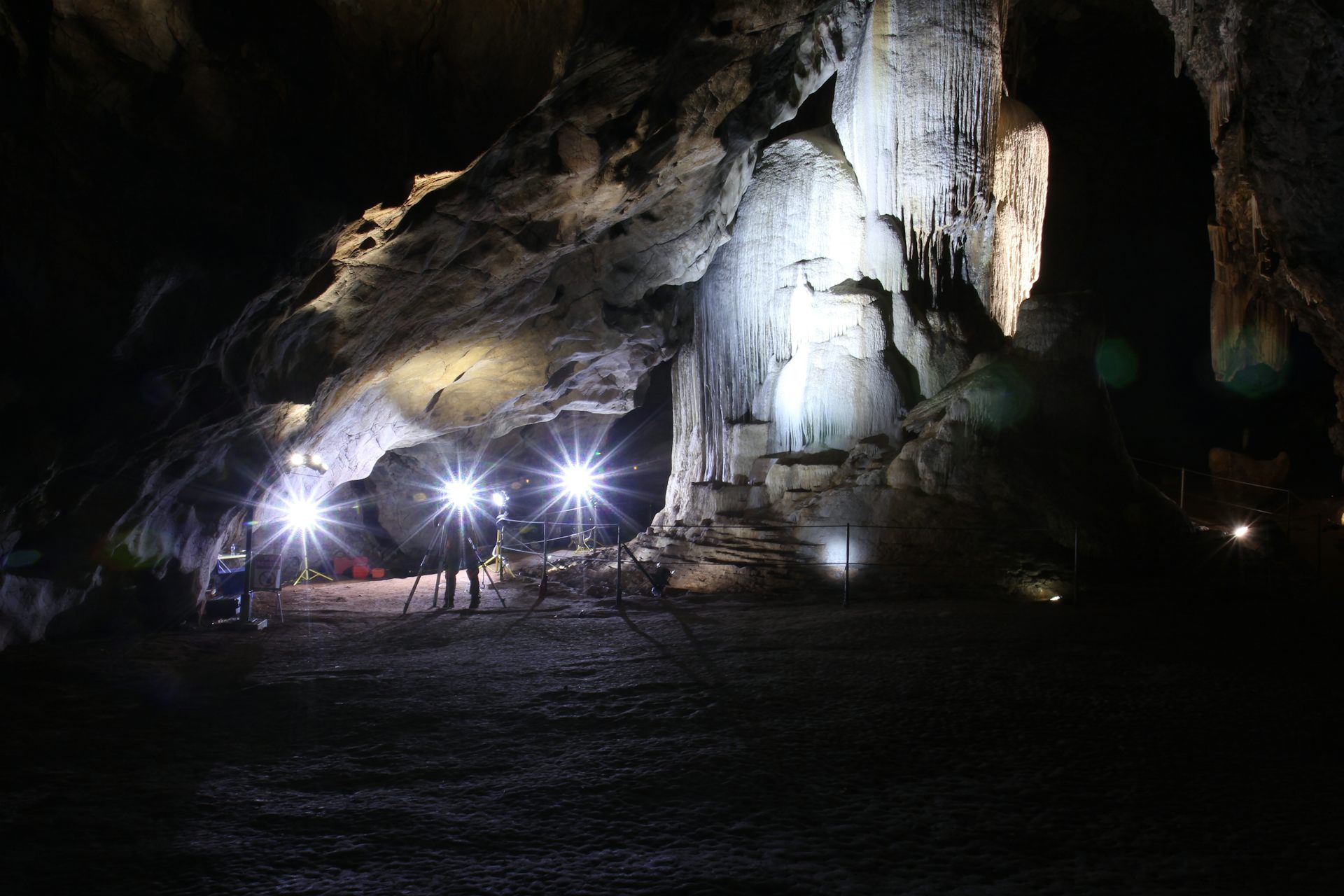Interior of a cave chamber, with a large stalagmite reaching from the floor to the roof