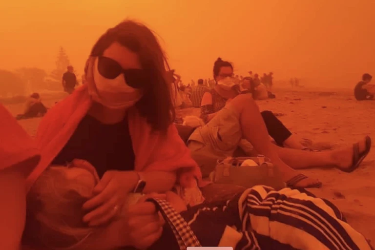 Woman with child evacuated on beach during bushfire