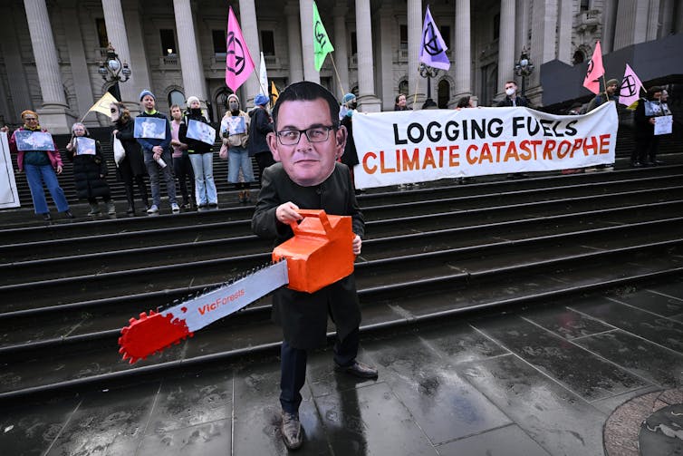 protesters with sign 'logging fuels climate catastrophe'