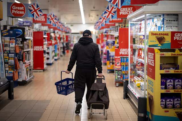 Man shopping in a supermarket aisle with lots of price reductions