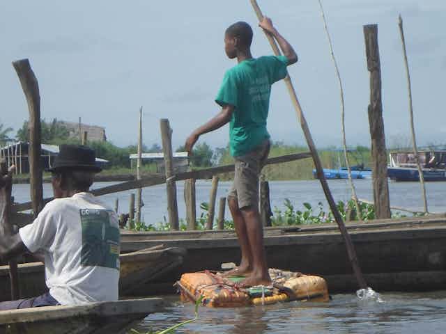 Deux garçons sur des radeaux en train de se déplacer sur le lac.