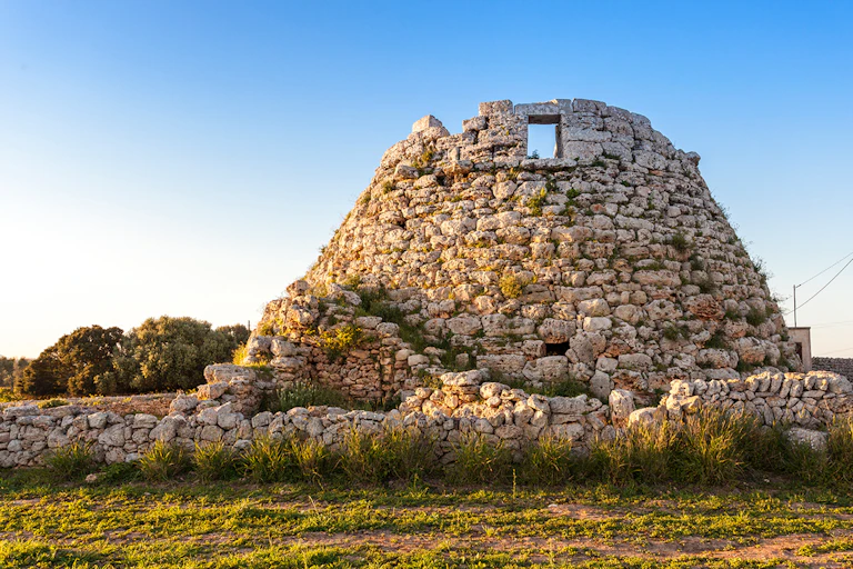 Una construcción de piedra en forma de cono con una puerta en la parte de arriba.