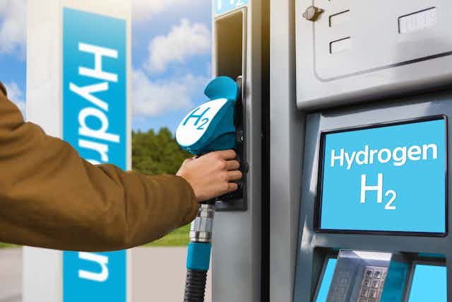 A hand reaching for a fuel pump with a H2 label, beside a screen that says "Hydrogen H2".