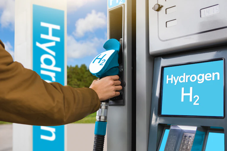 A hand reaching for a fuel pump with a H2 label, beside a screen that says "Hydrogen H2".