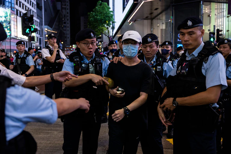Hong Kong police detain a Tiananmen Square protestor wearing a COVID mask.