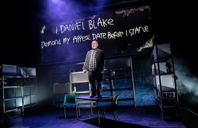 A man stands on a table on a stage.