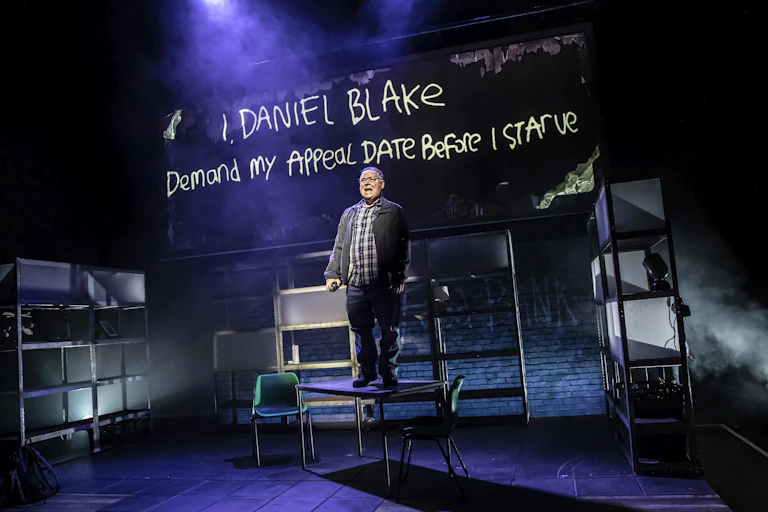 A man stands on a table on a stage.
