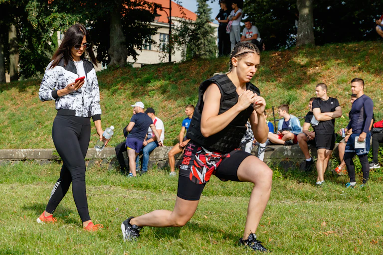 A young woman performs a lunge while wearing a weighted vest.