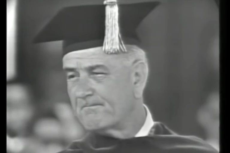 An elderly white is speaking at a college graduation.