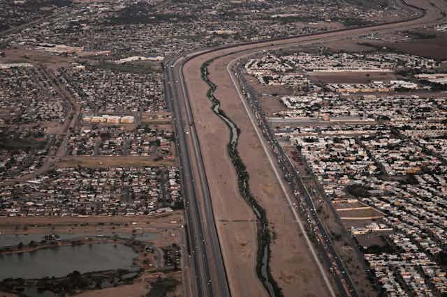 An aerial photo shows parallel roads, a small river, and towns on both sides.