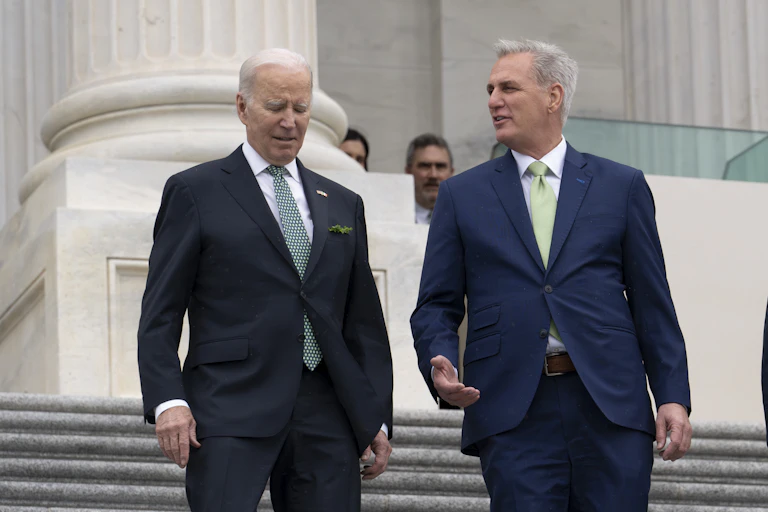 Two men in dark suits walking down stairs outside