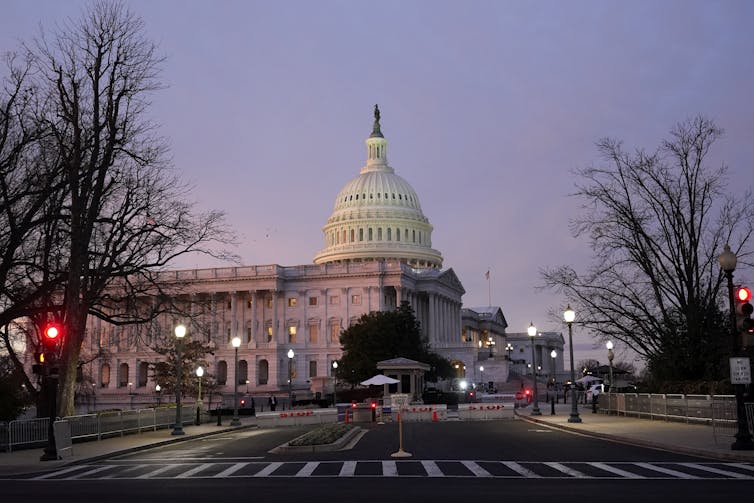 A white-domed building at the end of a large street.