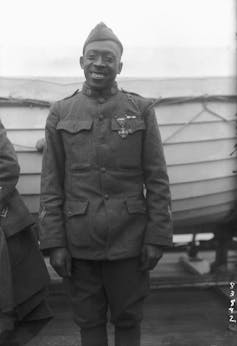 Un hombre negro vestido con uniforme militar sonríe después de recibir una medalla por su valentía.