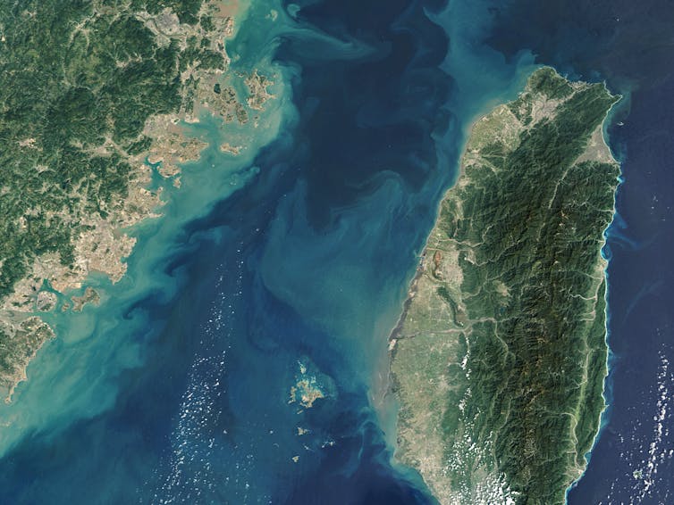 An aerial shot of the Taiwan Strait showing blue waters and two green land masses