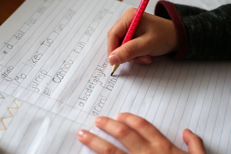 A child writes in an exercise book.