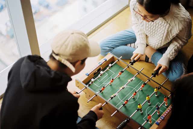 A photo of two people playing foosball
