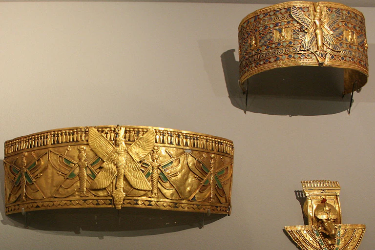 Three pieces of gold, intricately decorated jewelry in a museum display.