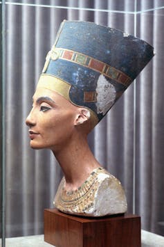 A faded but painted bust of a woman with an exaggerated, large hairdo.