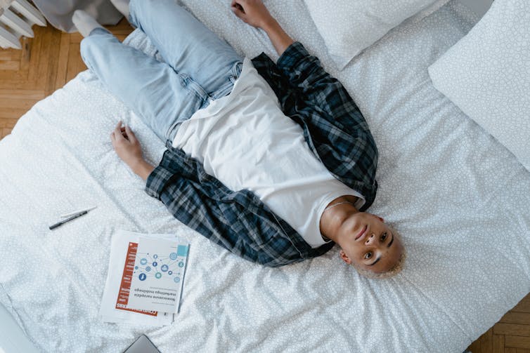 A young man lies across his bed.