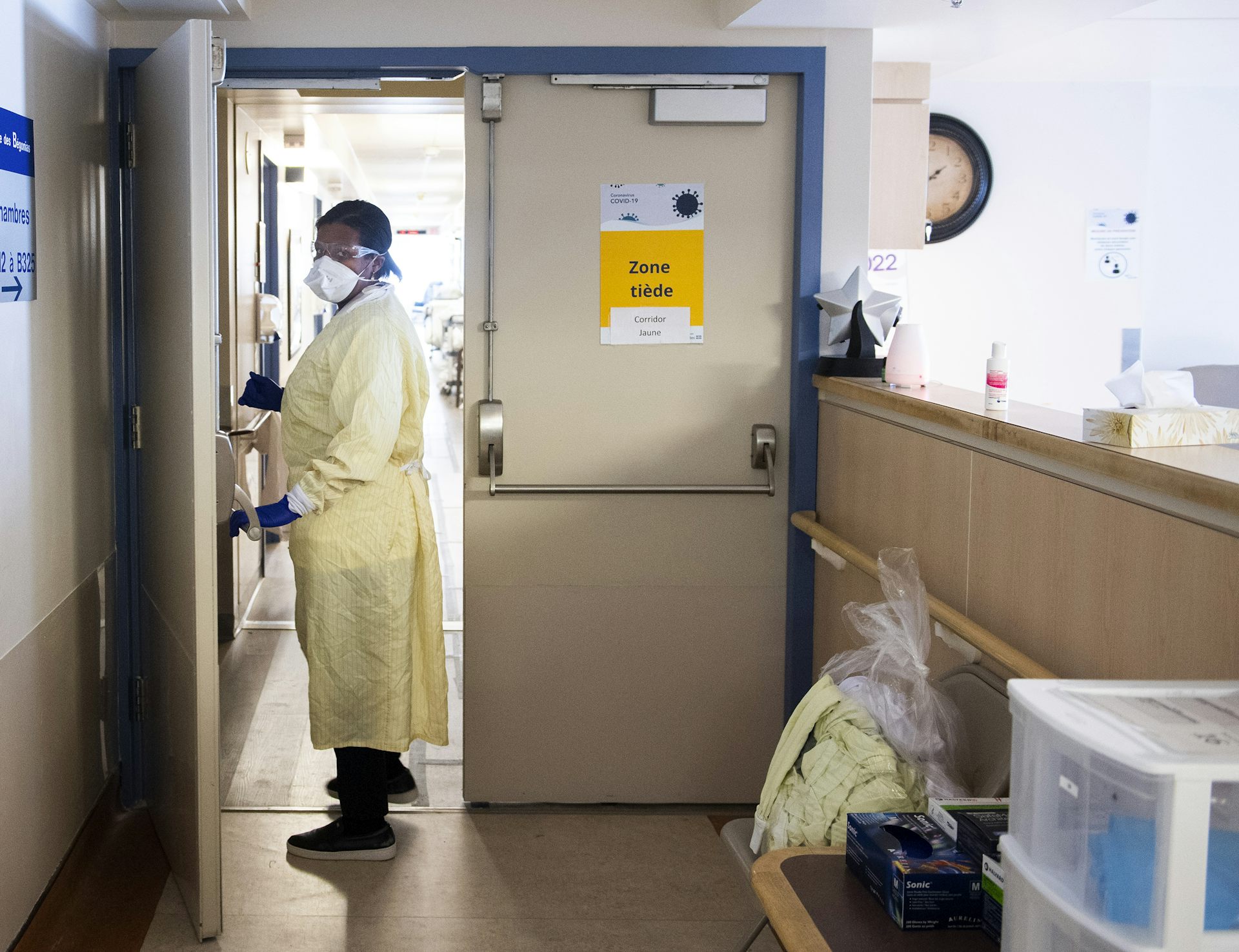 A person in personal protective gear in a doorway inside a long-term care facility