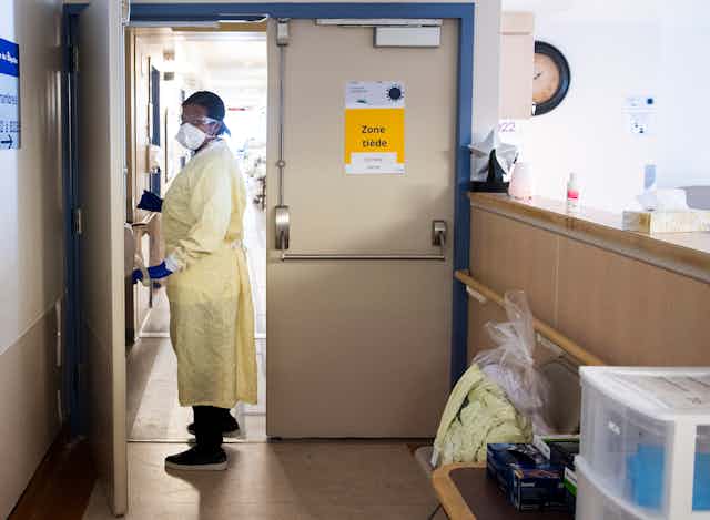 A person in personal protective gear in a doorway inside a long-term care facility