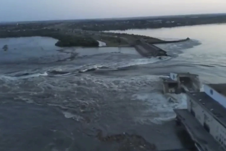 A grainy image shows water cascading through an open gap in a dam.