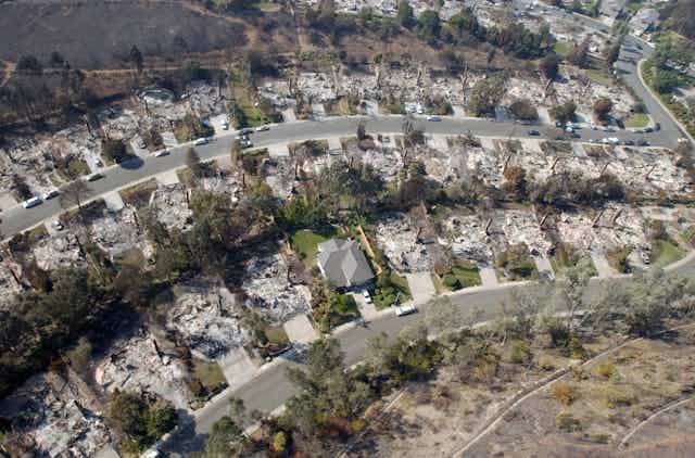 Dozens of burned homes lines a curving street in California. Only one house is still standing.