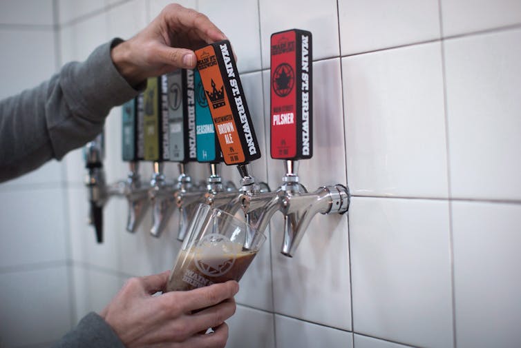 A man's hands are seen pouring a glass of beer from a tap.