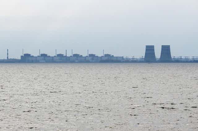 a power plant seen in the distance across a body of water