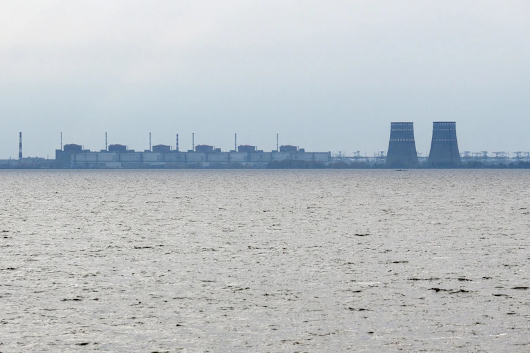 a power plant seen in the distance across a body of water