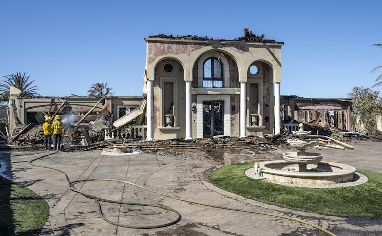 Firefighters work on the remains of a high-end home, with its elaborate front entrance and fountain out front being about all the remains from a 2022 fire near Los Angeles that's recognizable.