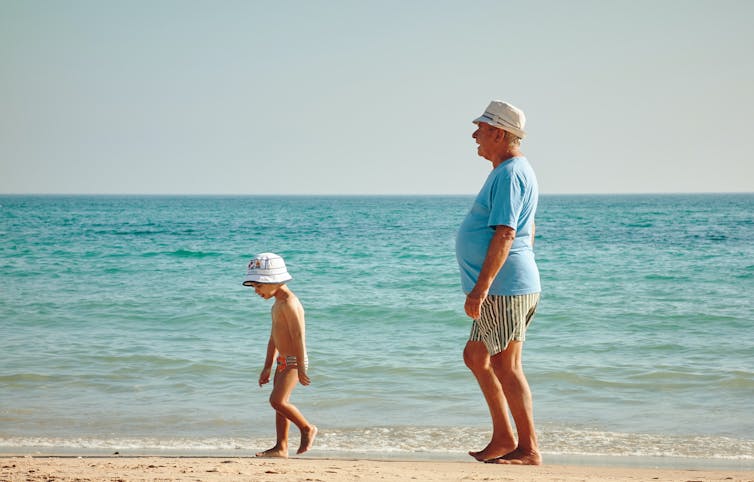 Child and grandfather walk on a beach