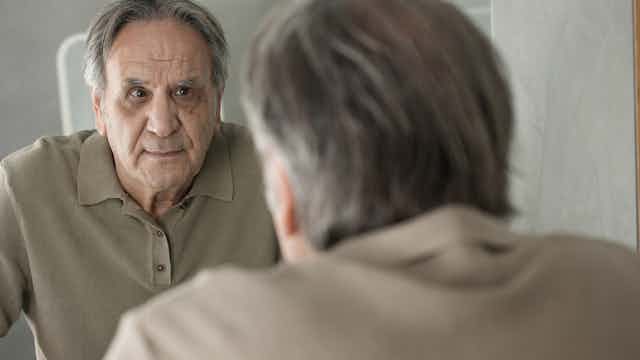Older man looks in the mirror