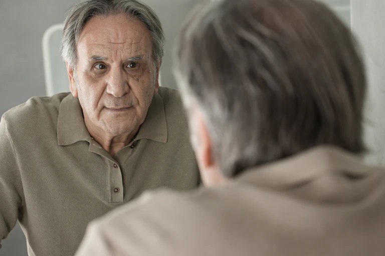Older man looks in the mirror